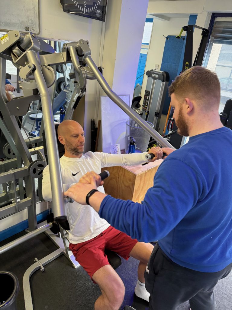 Personal Trainer for Shoulder Pain Hale | Soma Fitness Personal trainer coaching a client through an upper-body strength exercise at Soma Fitness near Hale