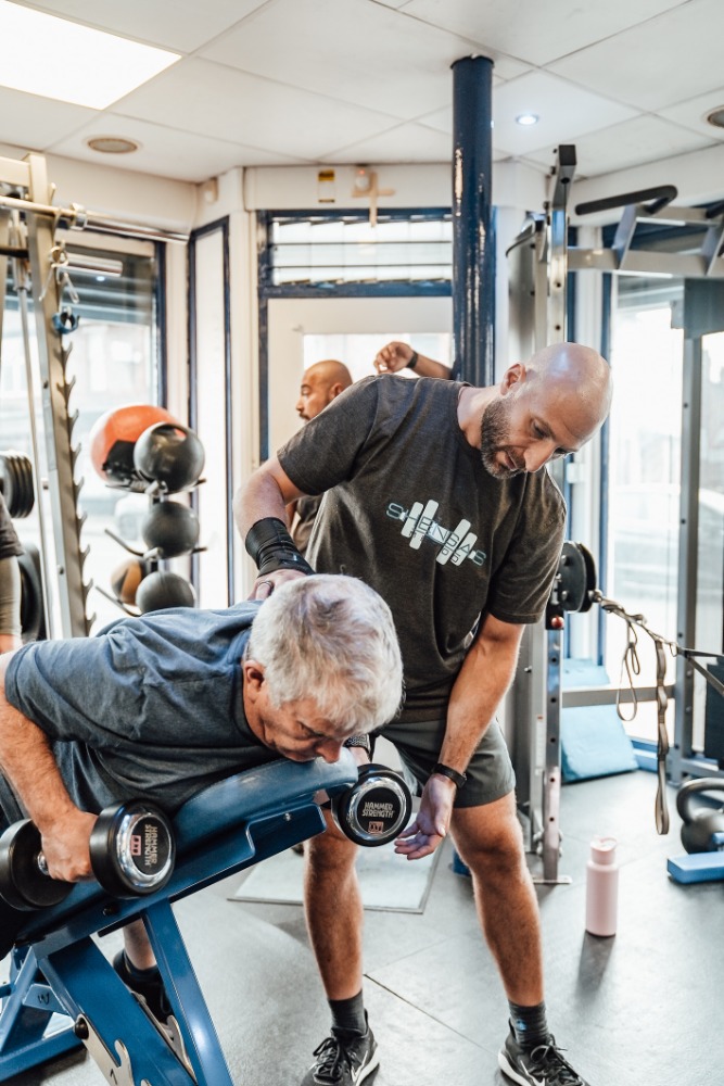 Personal trainer coaching an older adult through strength training at Soma Fitness in Altrincham Personal trainer coaching an older adult through strength training at Soma Fitness in Altrincham